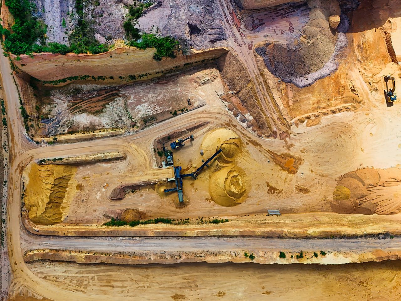 Home Aerial shot of a quarry with machinery extracting and processing materials.