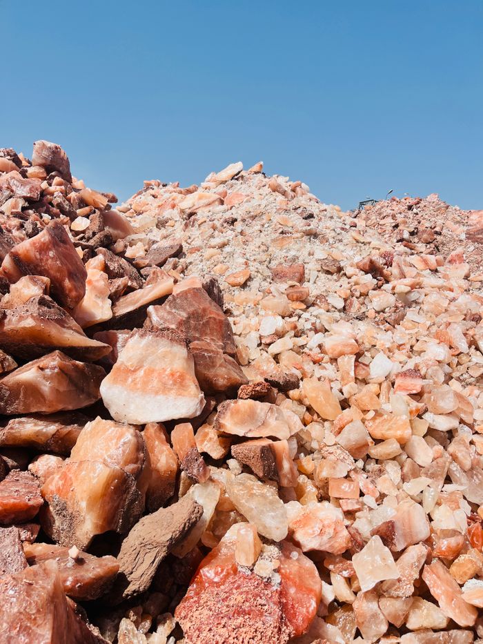 Close-up of pink and orange Himalayan salt rock piles with a clear blue sky backdrop.